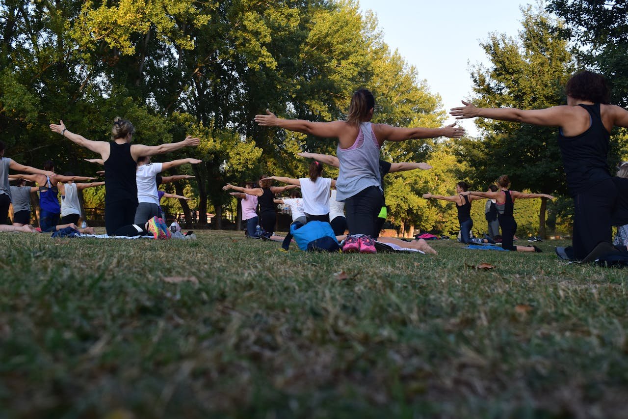 services-bg Group of adults practicing yoga outdoors in a park surrounded by trees.