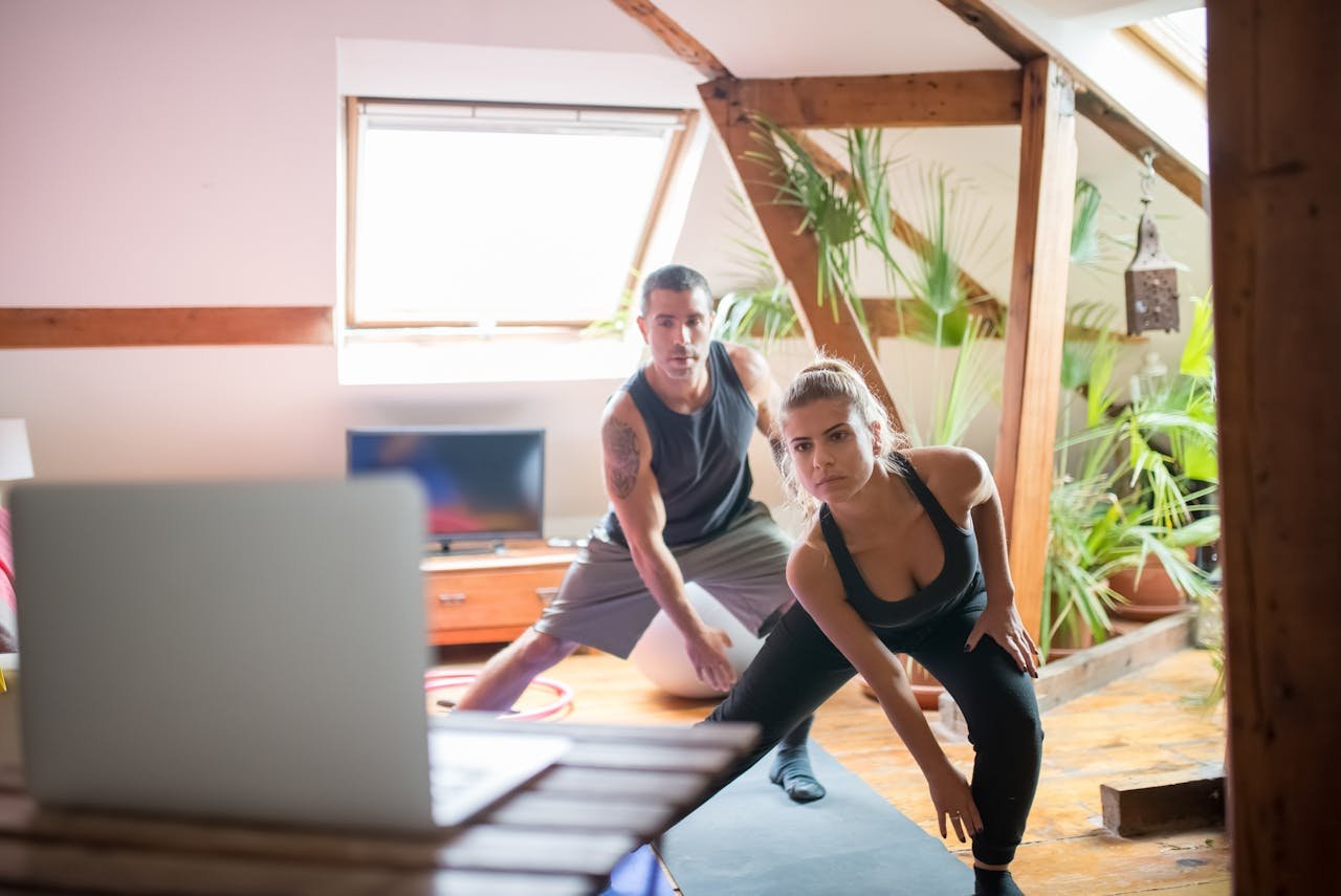 get-in-touch A man and woman working out at home using a laptop for guided exercises. Indoor active lifestyle.